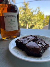 a white plate with a brownie and a bottle of whisky